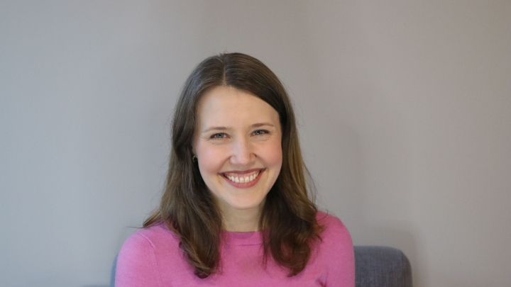 Photo of Jaclyn Donahue, woman with long dark hair, a bright pink top and big smile