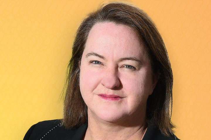 Close up photo of WGEA CEO Mary Wooldridge's face with long dark hair on a yellow background