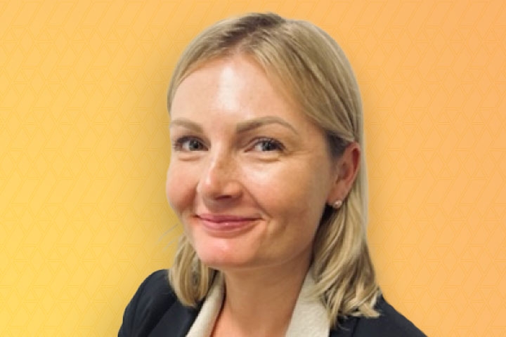 Close up photo of Tori Gooding's face at a slight angle to camera, with short blond hair, and a yellow background